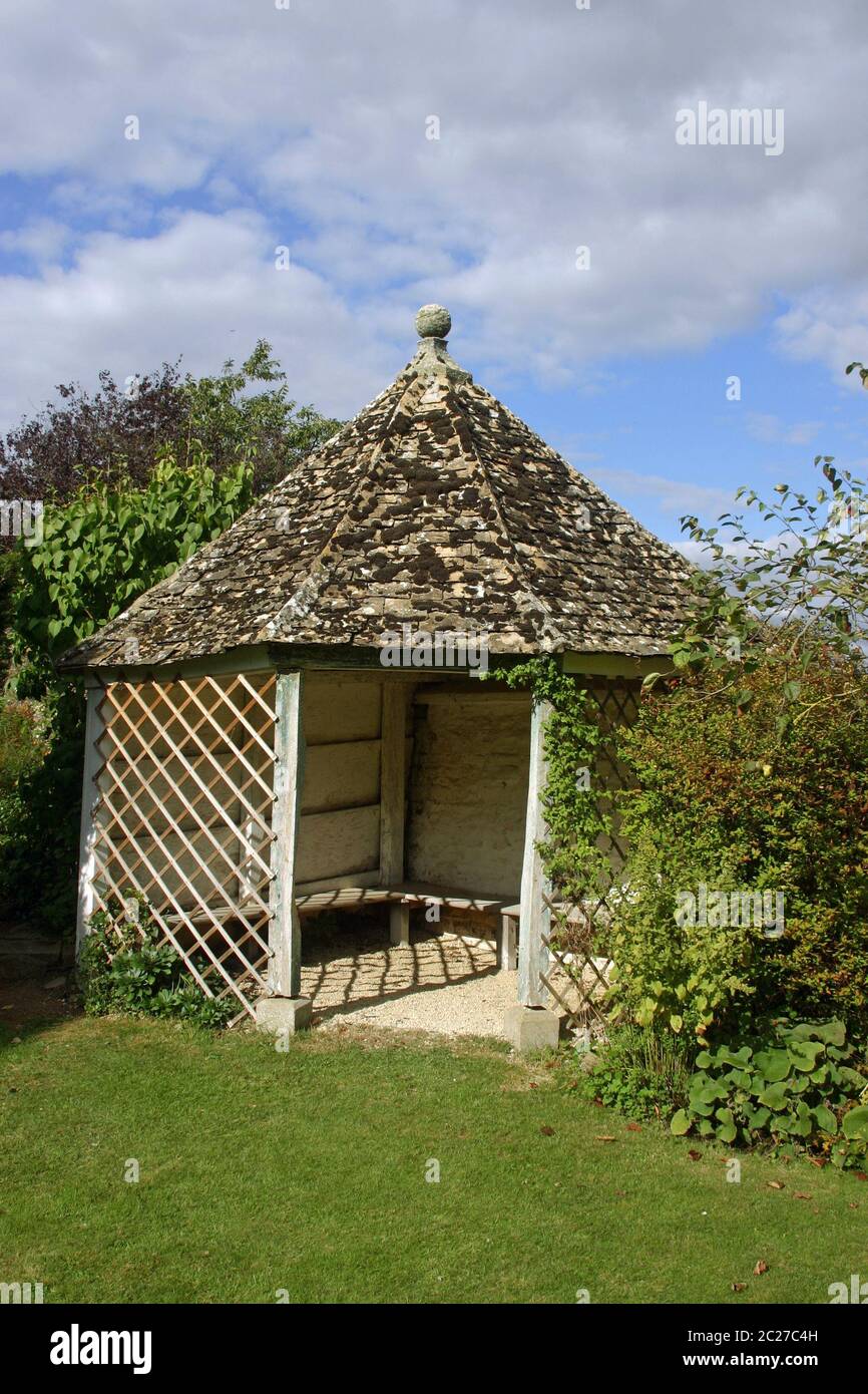 Wooden gazebo with trellis at the sides in a garden with lawn in front