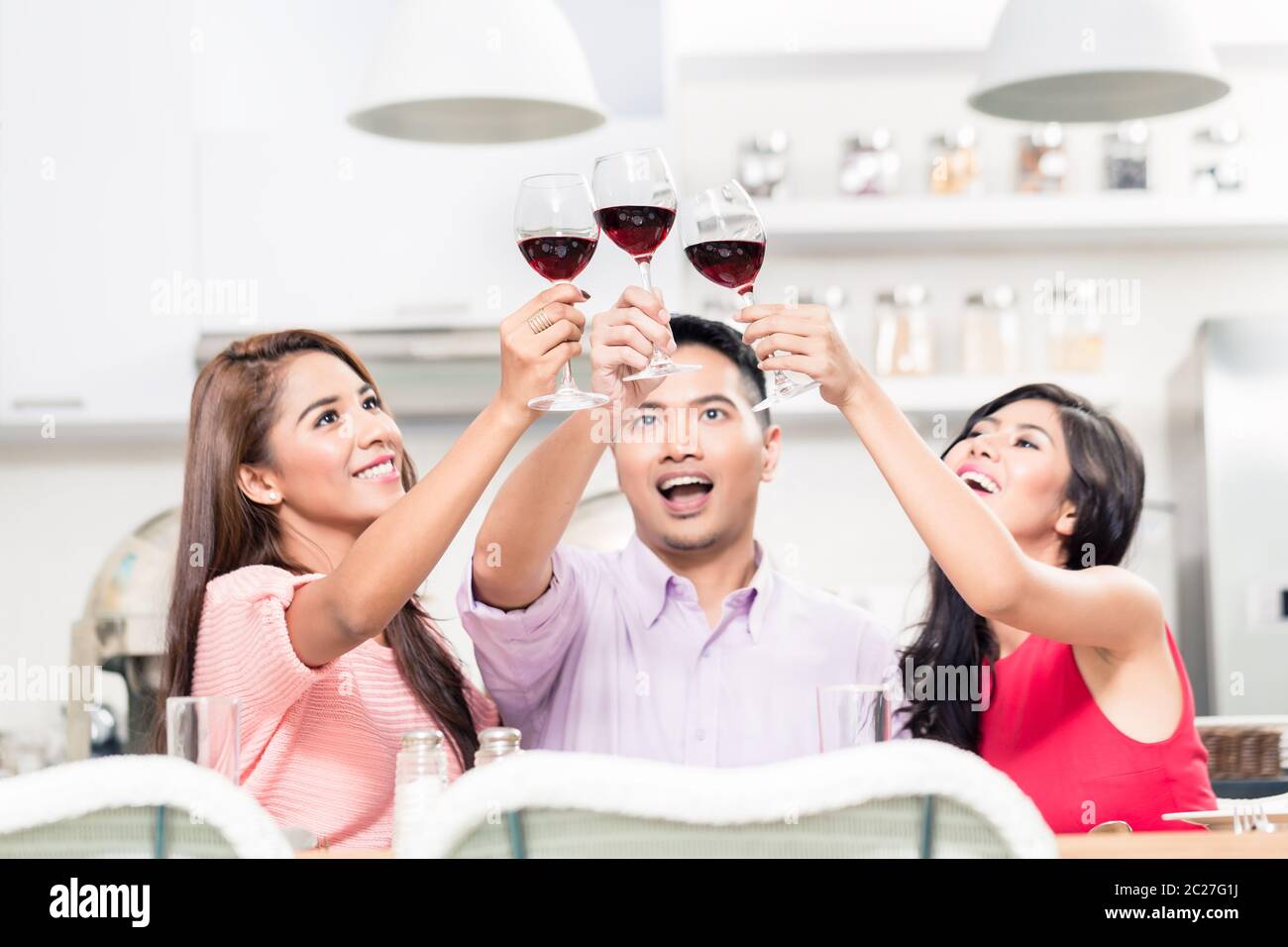 Close-up of cheerful friends holding wine glasses raising toast in the bar Stock Photo