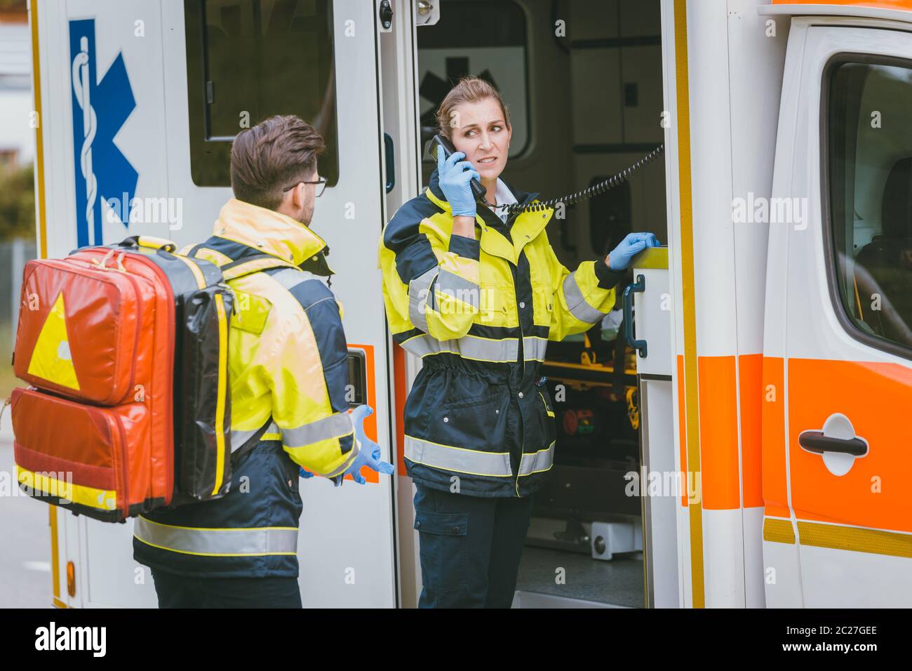 Medics in front of ambulance talking to headquarters using radio communication Stock Photo