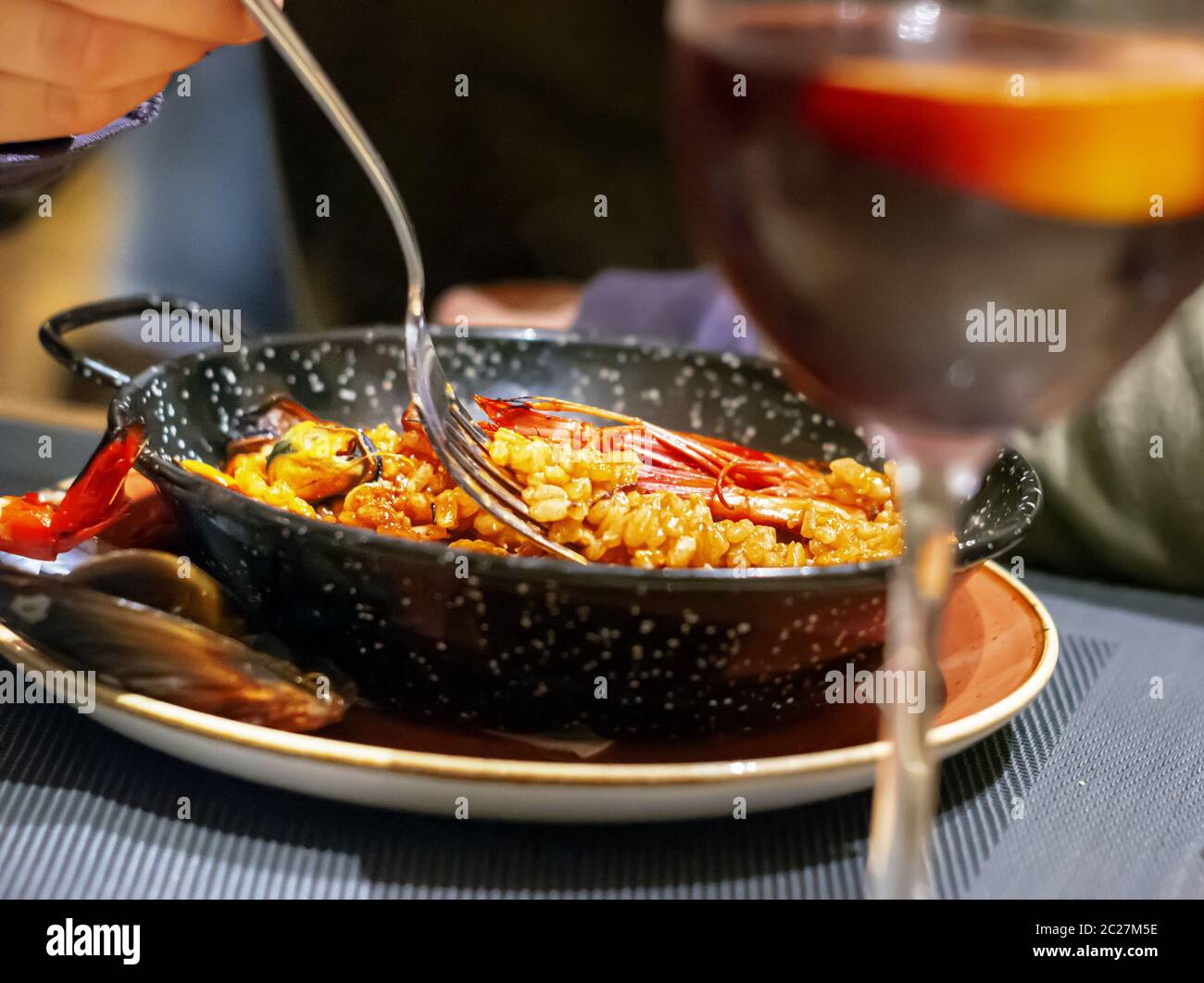 eating Valencian paella in a black pan using a fork Stock Photo