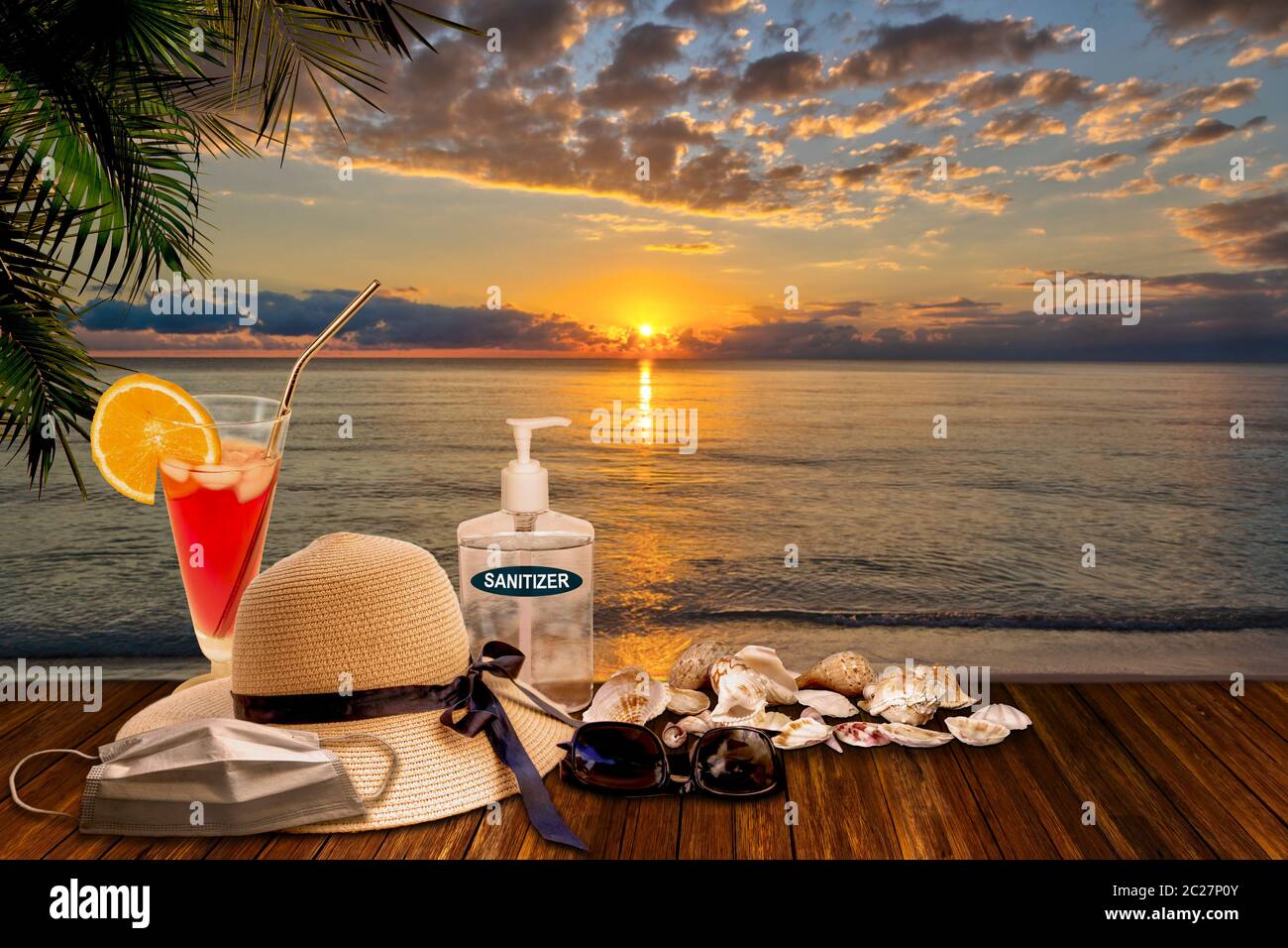 Vacationing in the New Normal after COVID-19 coronavirus pandemic. Tourism concept showing sunset beach with hand sanitizer, medical face mask among b Stock Photo