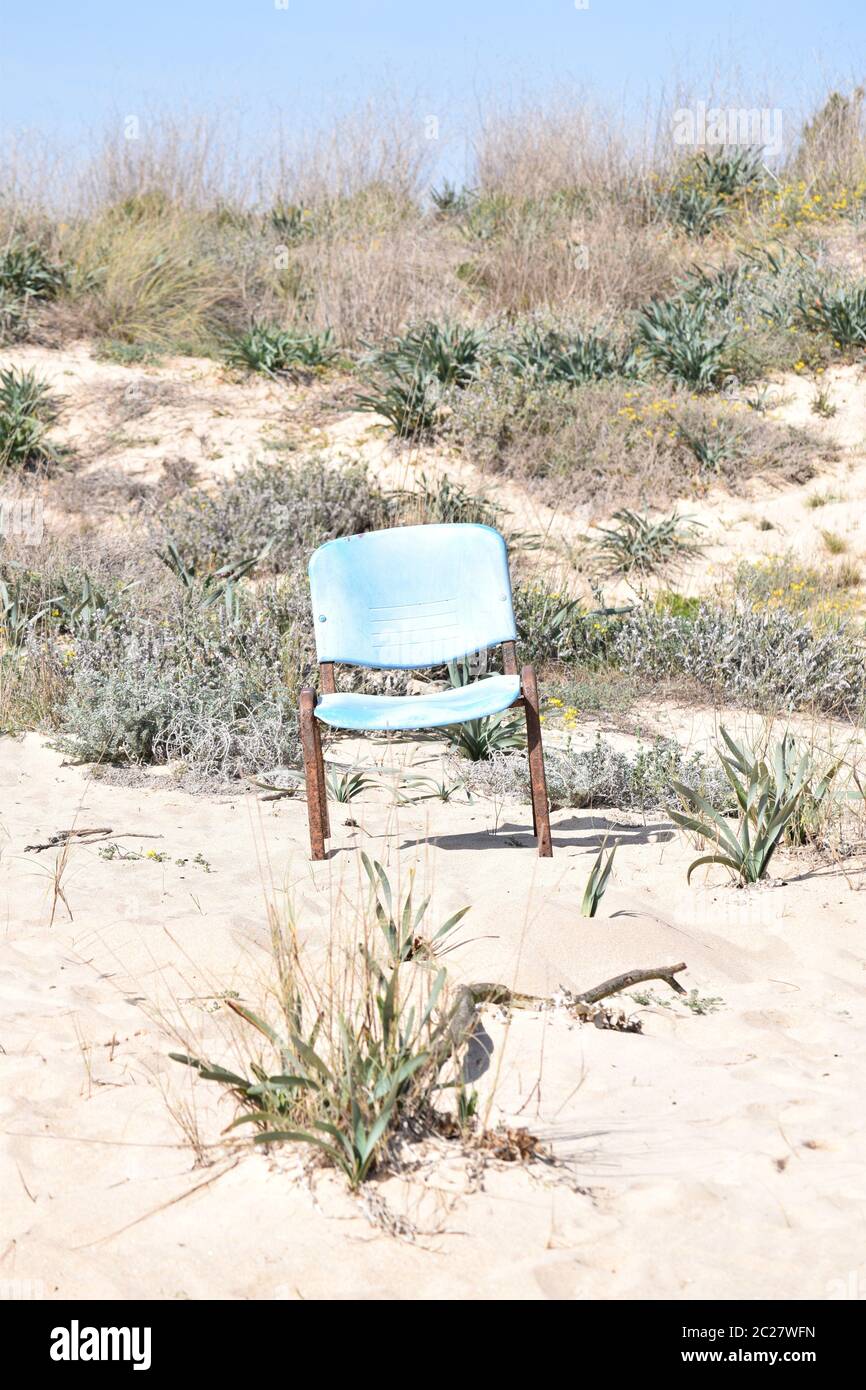 Old and rusty chair standing alone on the beach in the dunes Stock