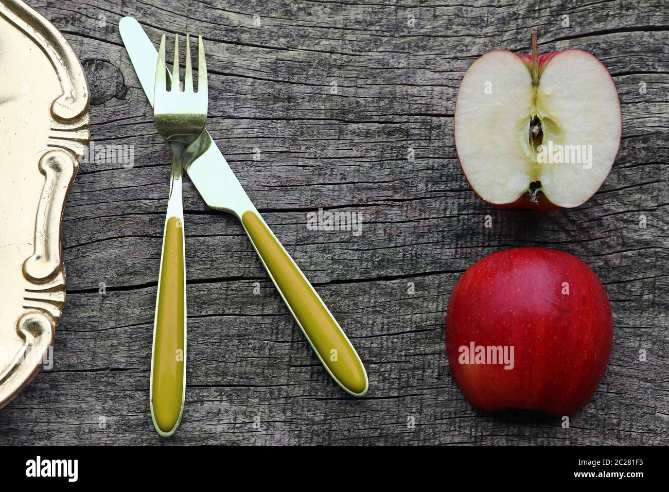 Two half apples, cutlery and plate on an old wooden table Stock Photo