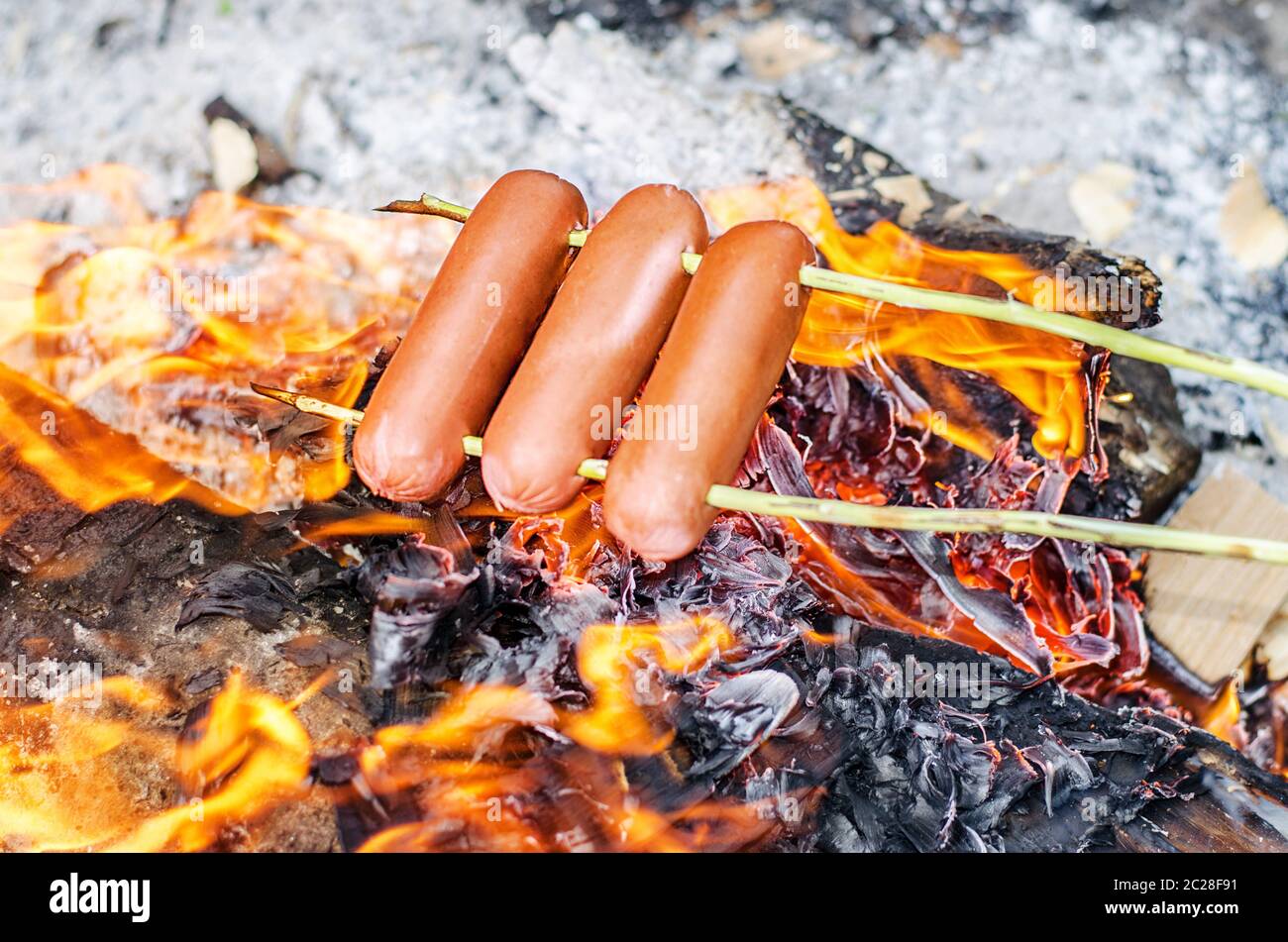 Grilling sausages over an open fire outdoors. Stock Photo