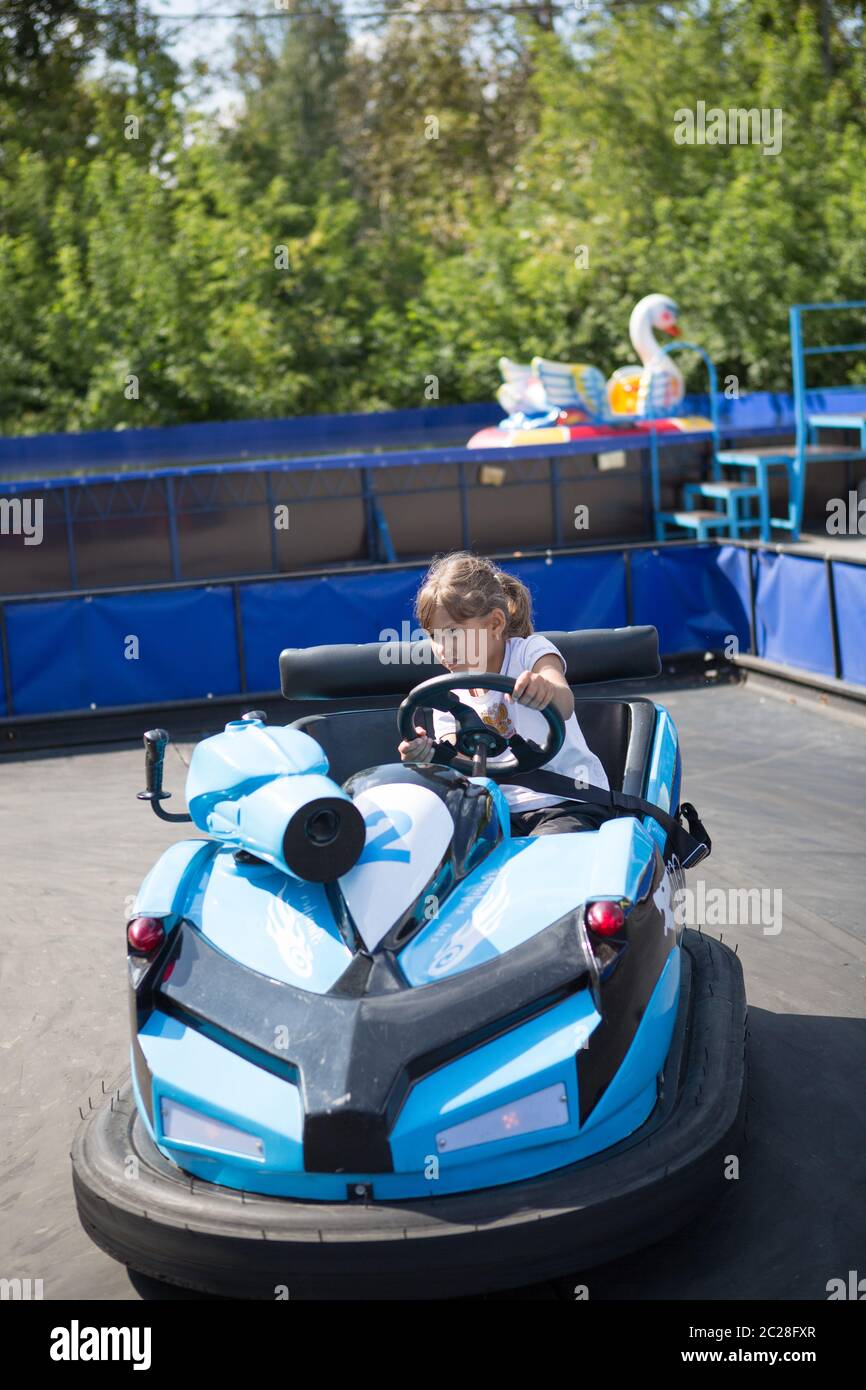 Little girl rides on toy electric cars blue in the Park Stock Photo