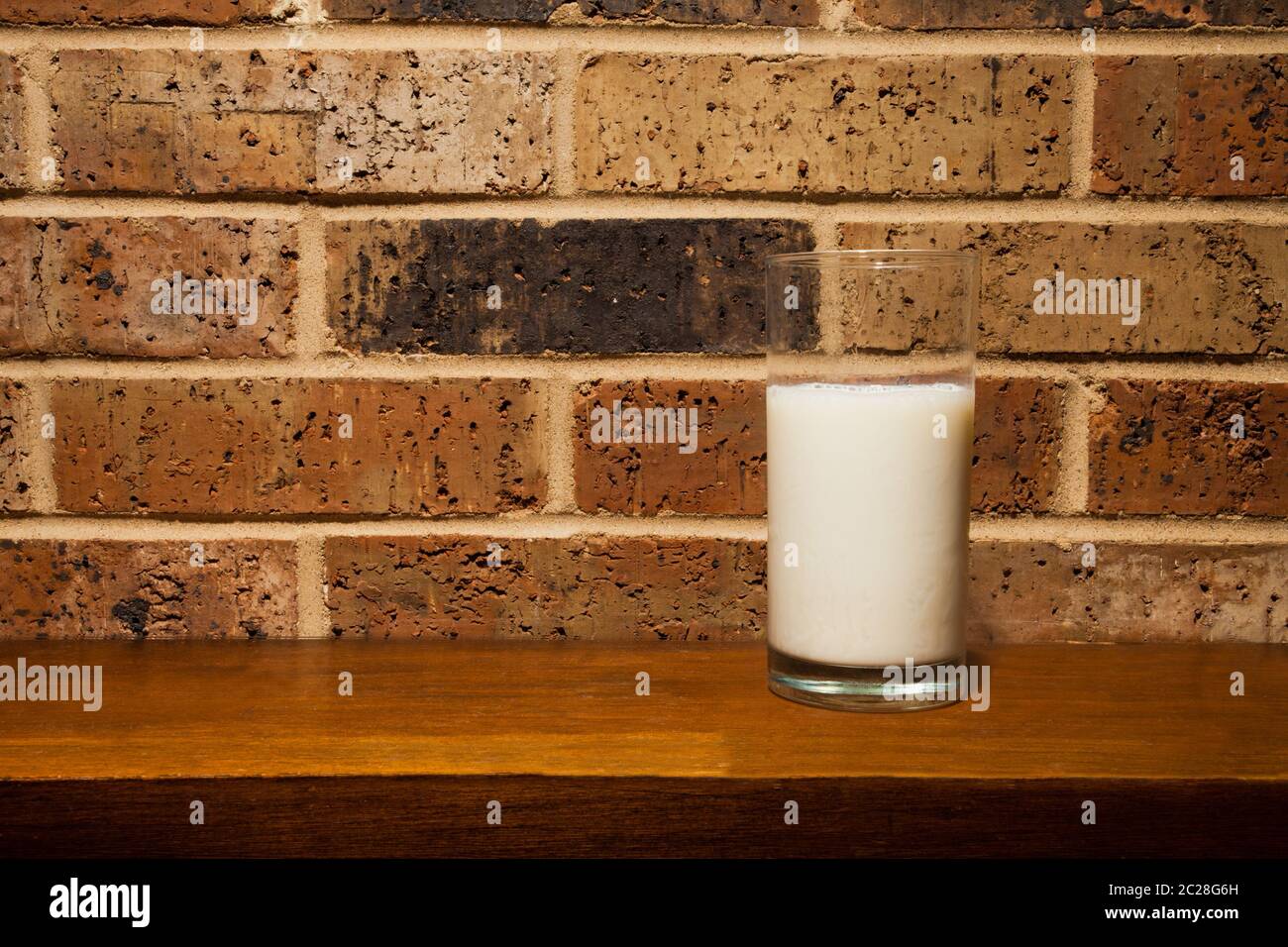 Glass of milk against a brick wall Stock Photo