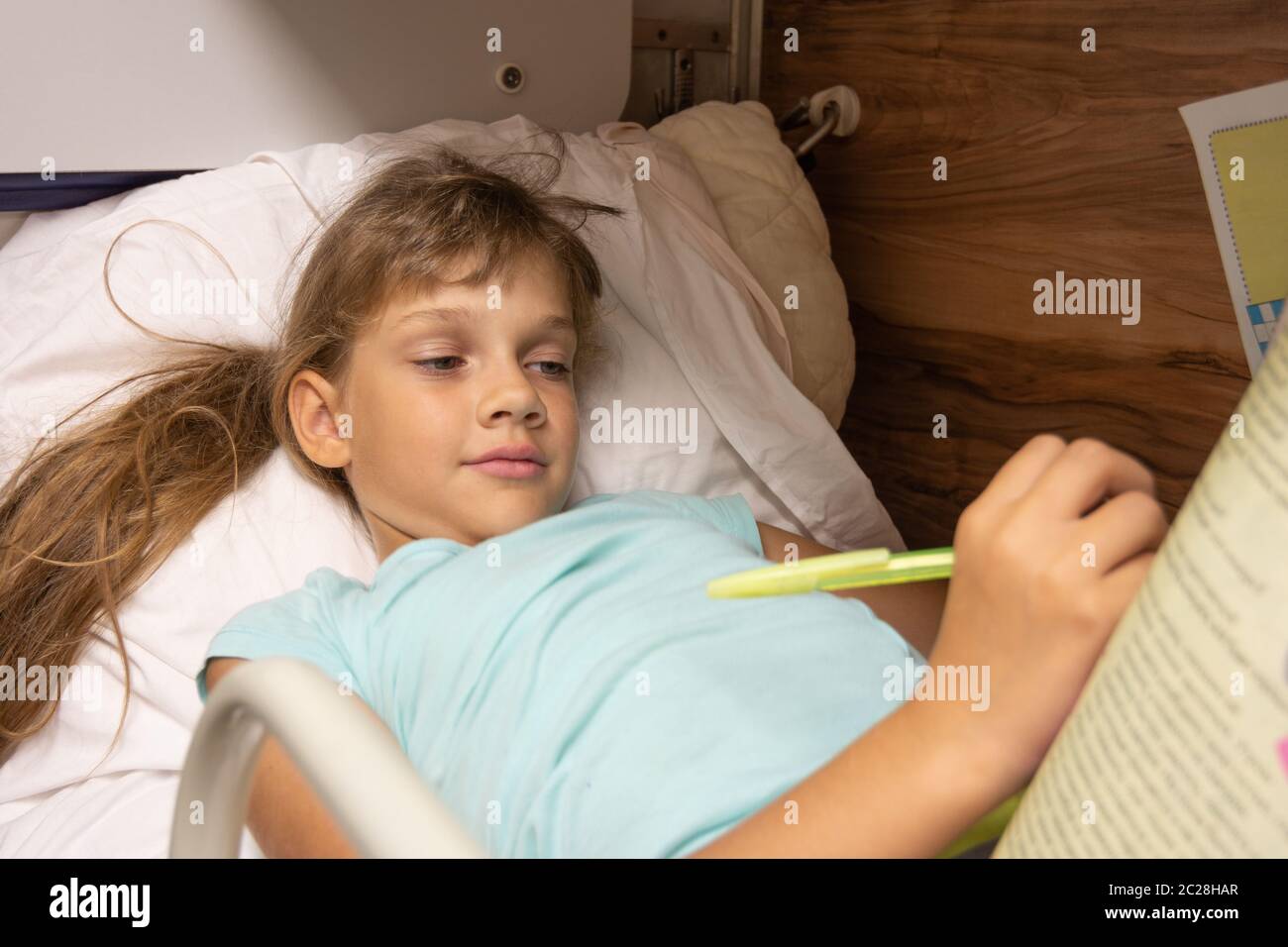 Girl solves a crossword puzzle on the top shelf of a reserved seat car
