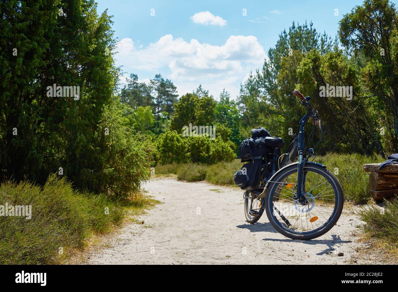 Trekking bike loaded with panniers on a sandy path through the heath in northern Germany Stock Photo