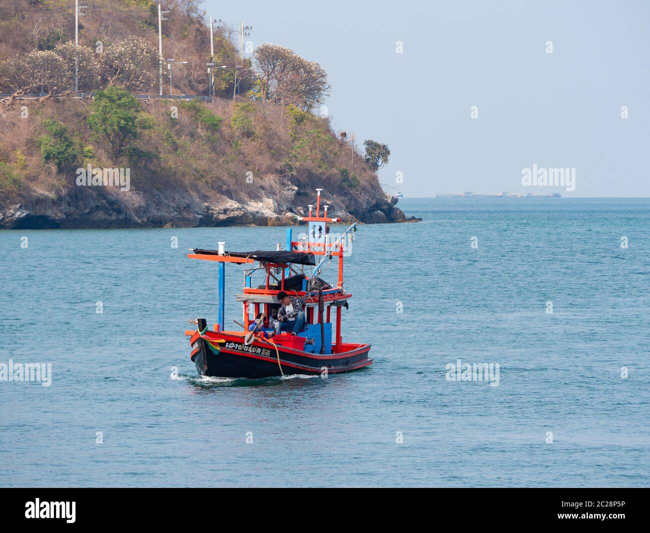 Small fishing vessel with three people on board at Ko Sichang off the coast of Chonburi Province in Thailand Stock Photo