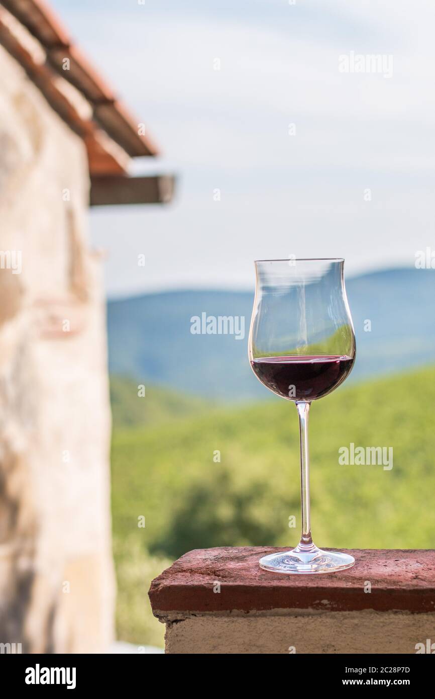 Glass of red wine at Tuscany. Wine yards in the background. Stock Photo