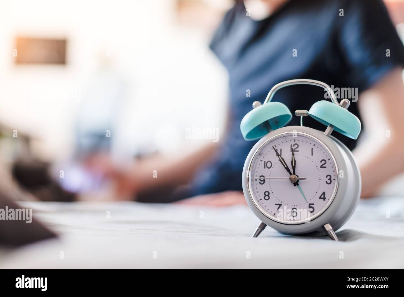 Alarm clock in the morning. Young wakes up and stretches in the blurry background. Stock Photo