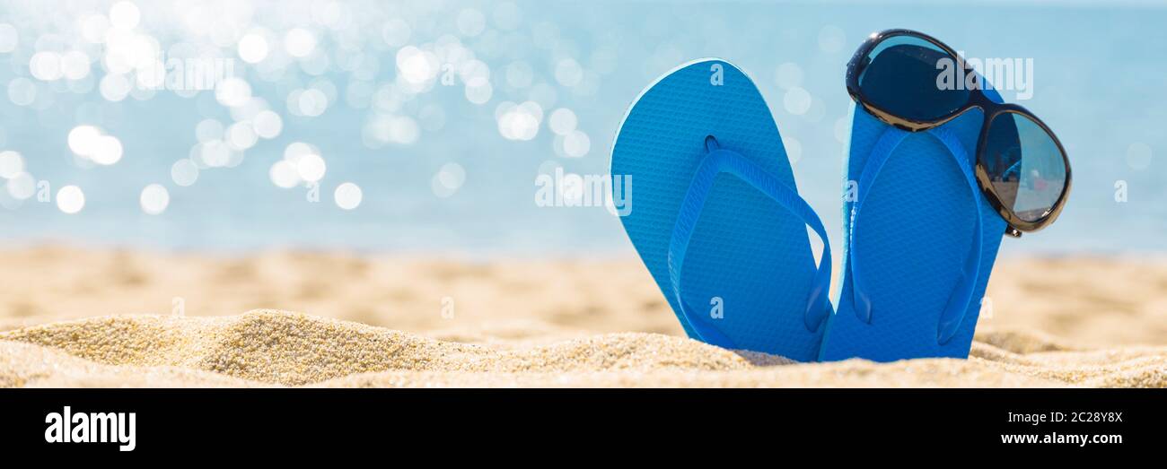 flip flops with sun glasses on the sandy tropical beach Stock Photo