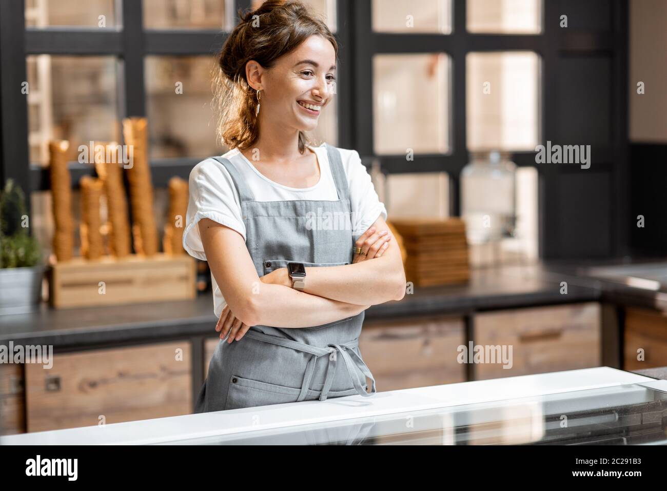 Portrait of a young and happy saleswoman at the counter in ice cream shop or cafe. Concept of a small business and retail Stock Photo