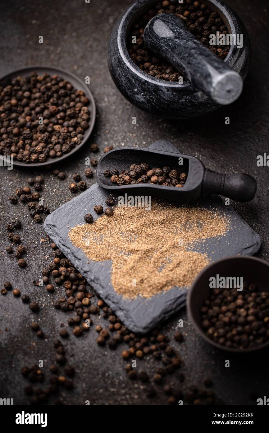 Black pepper corns and black pepper powder on dark background Stock