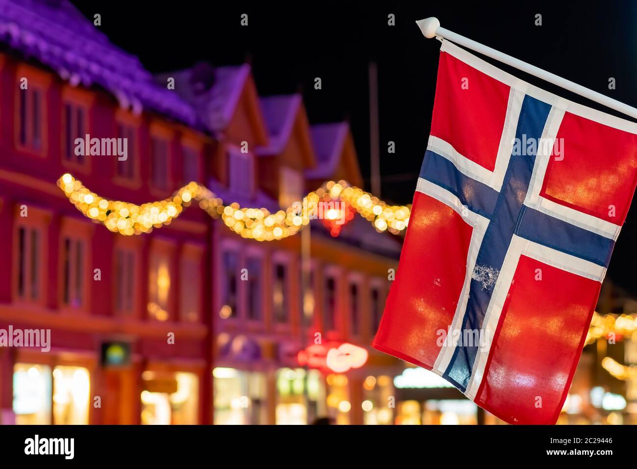 Norwegian flag hanging from a pole in Tromso city centre in Christmas period after dusk, Norway Stock Photo