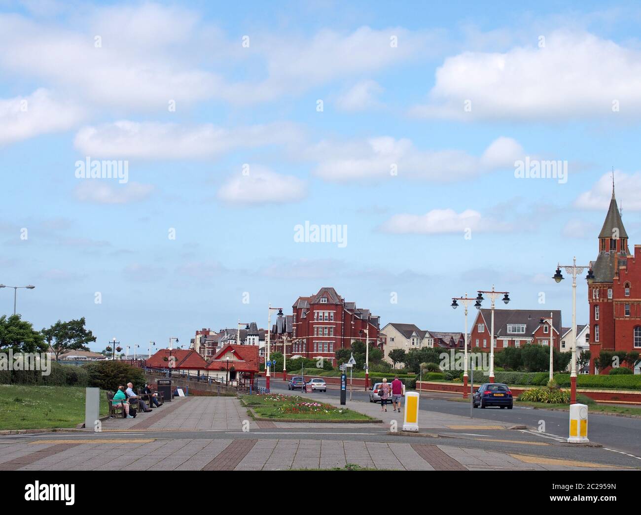 an older couple walking down marine drive in southport merseyside with old hotel buildings lining the street on a bright summer Stock Photo