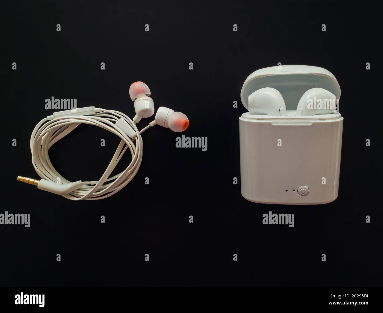 Comparison between classic wired headphones versus wireless earphones, air pods, isolated over black background. Pluses and minuses. Technology develo Stock Photo