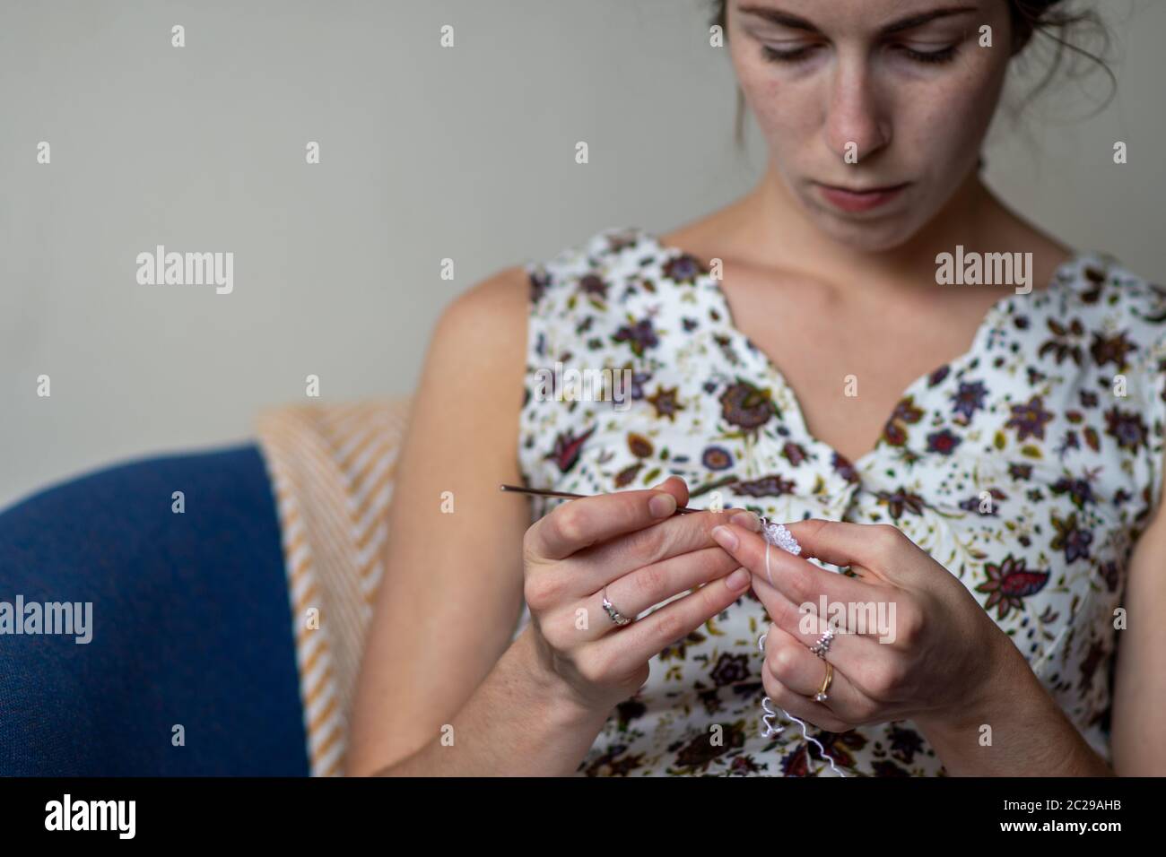 A young woman with crochet cotton and hook making something new craft hobby yarn wool design Stock Photo
