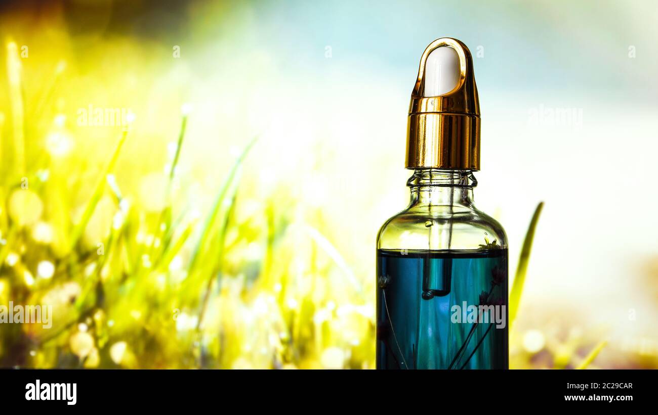 lemongrass essential oil dropping to glass bottles on natural green
