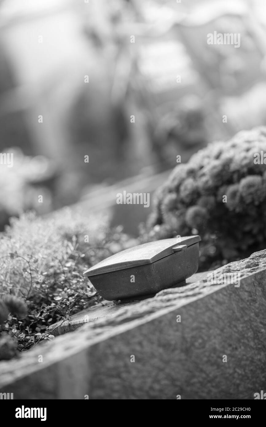 Holy water in iron bowl, cemetery, flowers Stock Photo