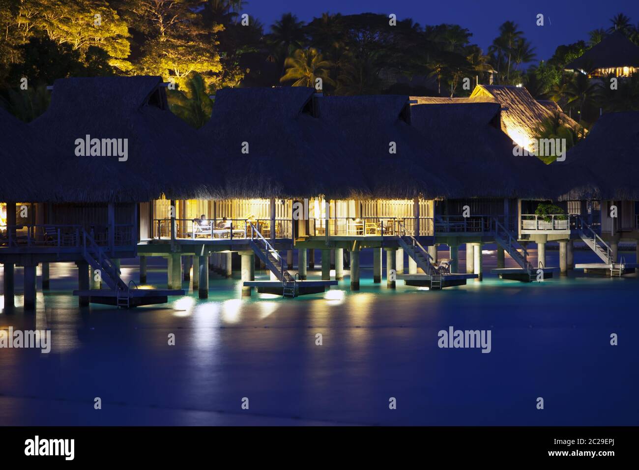 night landscape with houses over the water of the sea in backlight, Polynesia Stock Photo