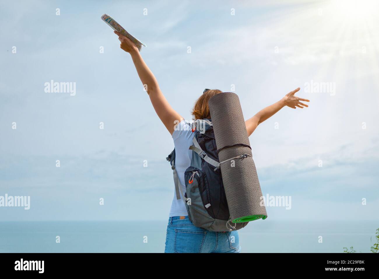 A woman tourist enjoys the achieved targets and beautiful view. Sun light. Stock Photo