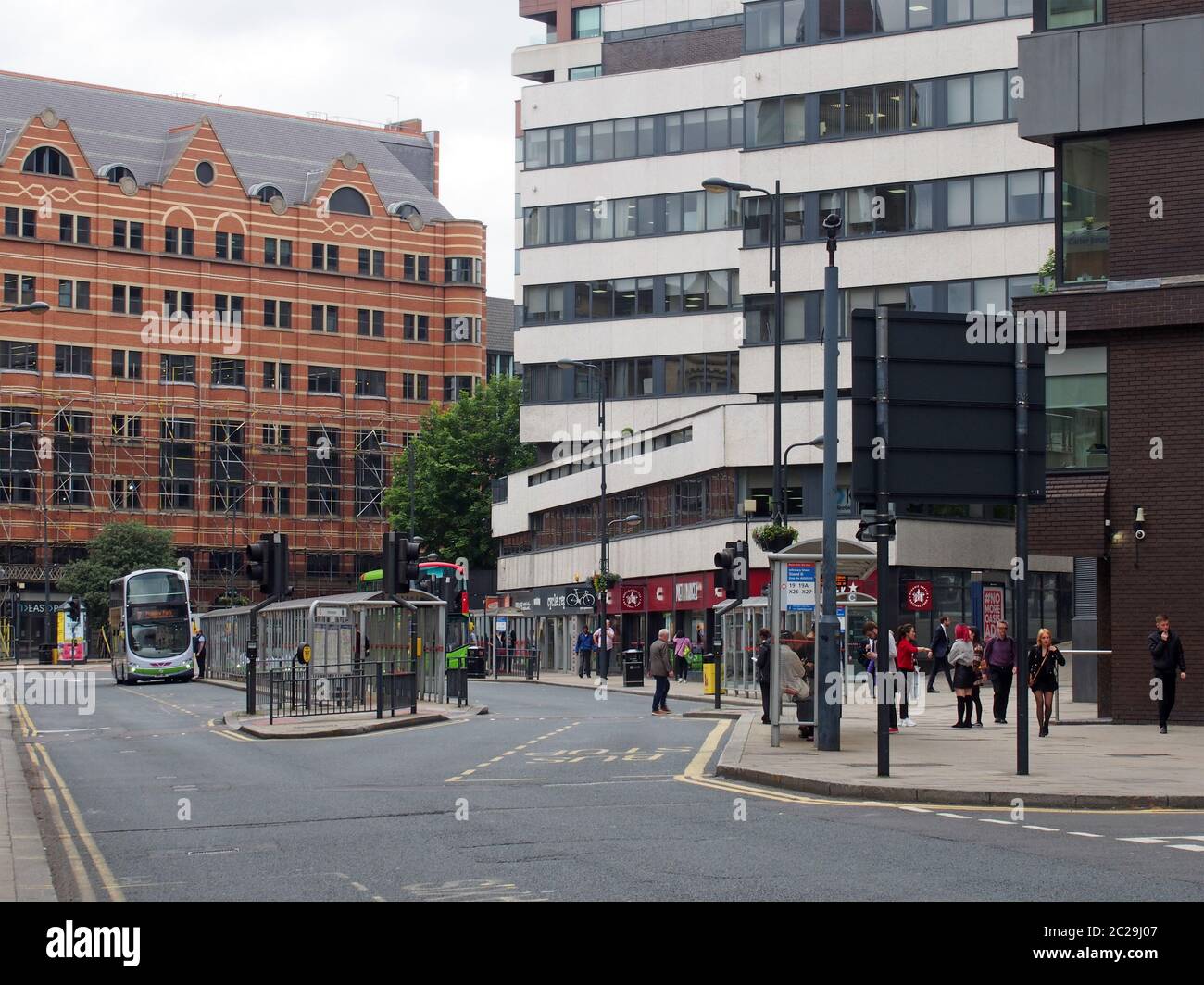 buses and pedestrians crossing the road in infirmary street leeds with surrounding office buildings Stock Photo
