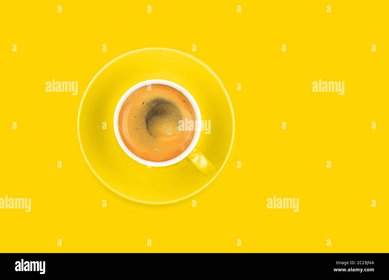 One full espresso coffee cup with saucer over vivid yellow paper ...