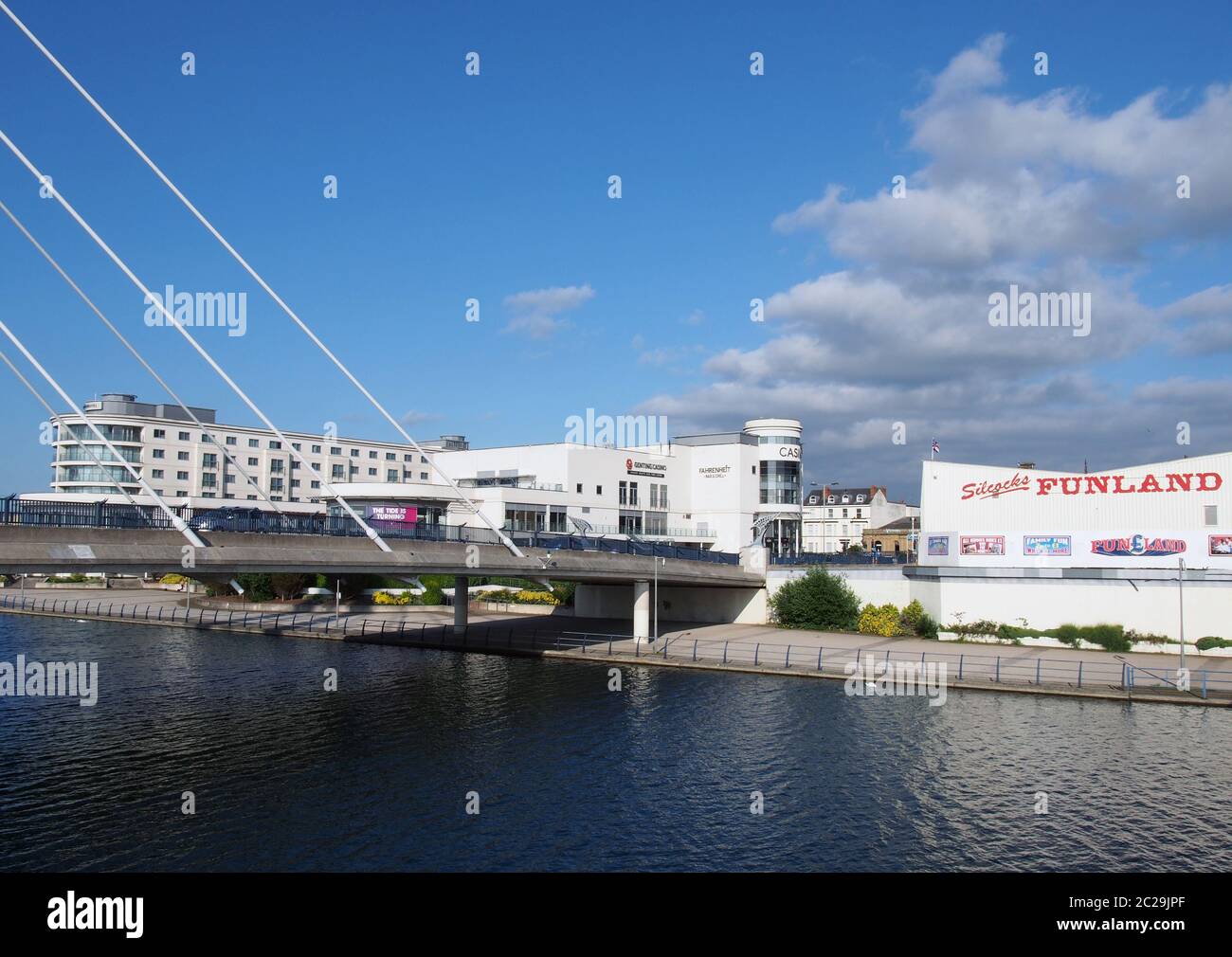 buildings along the shore of the lake in southport merseyside with hotels and amusement arcades between the suspension bridge Stock Photo