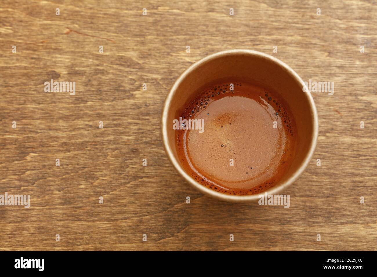 Close up one disposable brown paper cup full of espresso coffee on ...