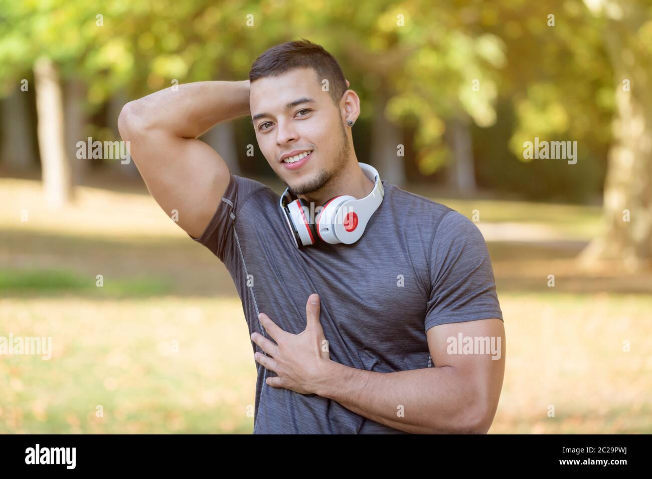 Flexing muscles posing runner young latin man running jogging sports training fitness workout copyspace copy space outdoor Stock Photo
