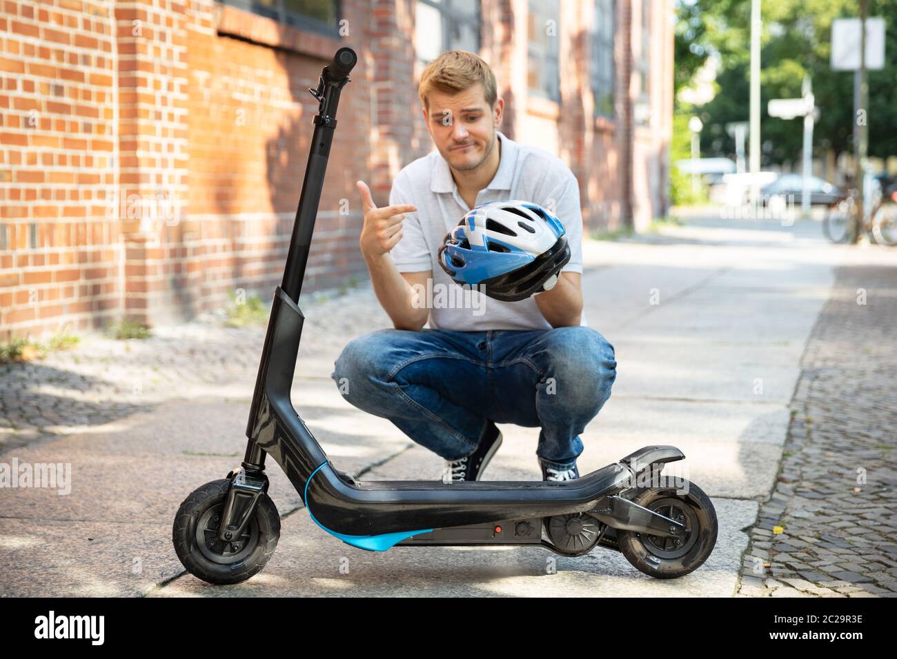 Man Complaining About Having To Wear Helmet For E-Scooter Stock Photo