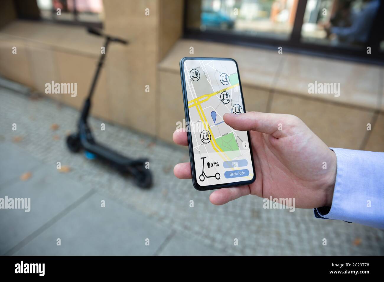 Young Man Using App To Rent Electric Scooter Stock Photo