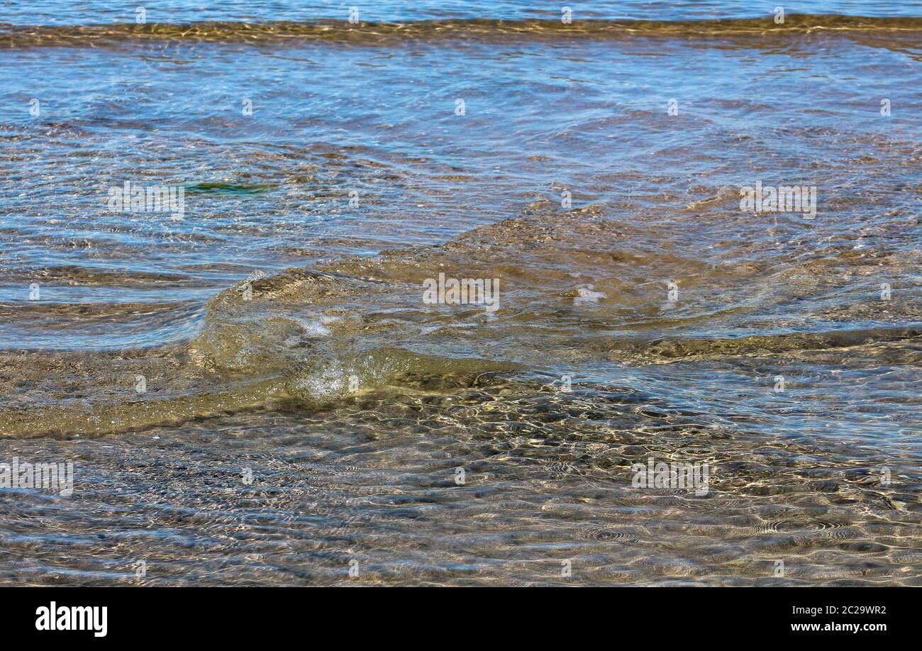 Small vortices in the crystal clear waters of the sea on the shore. Stock Photo