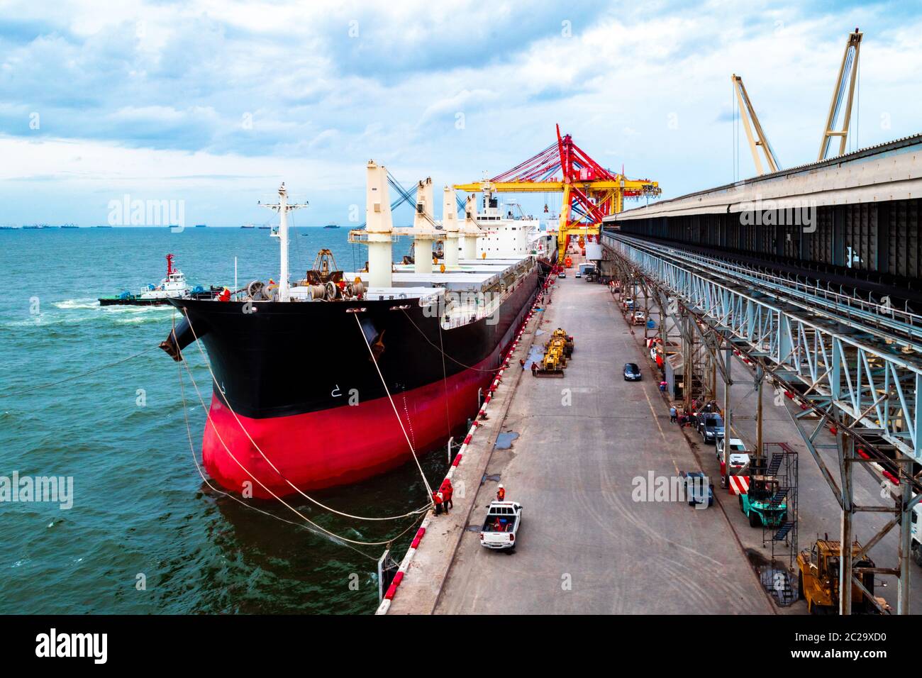 Large bulk cargo ship berthing at port discharging cargo. Truck leaving ...