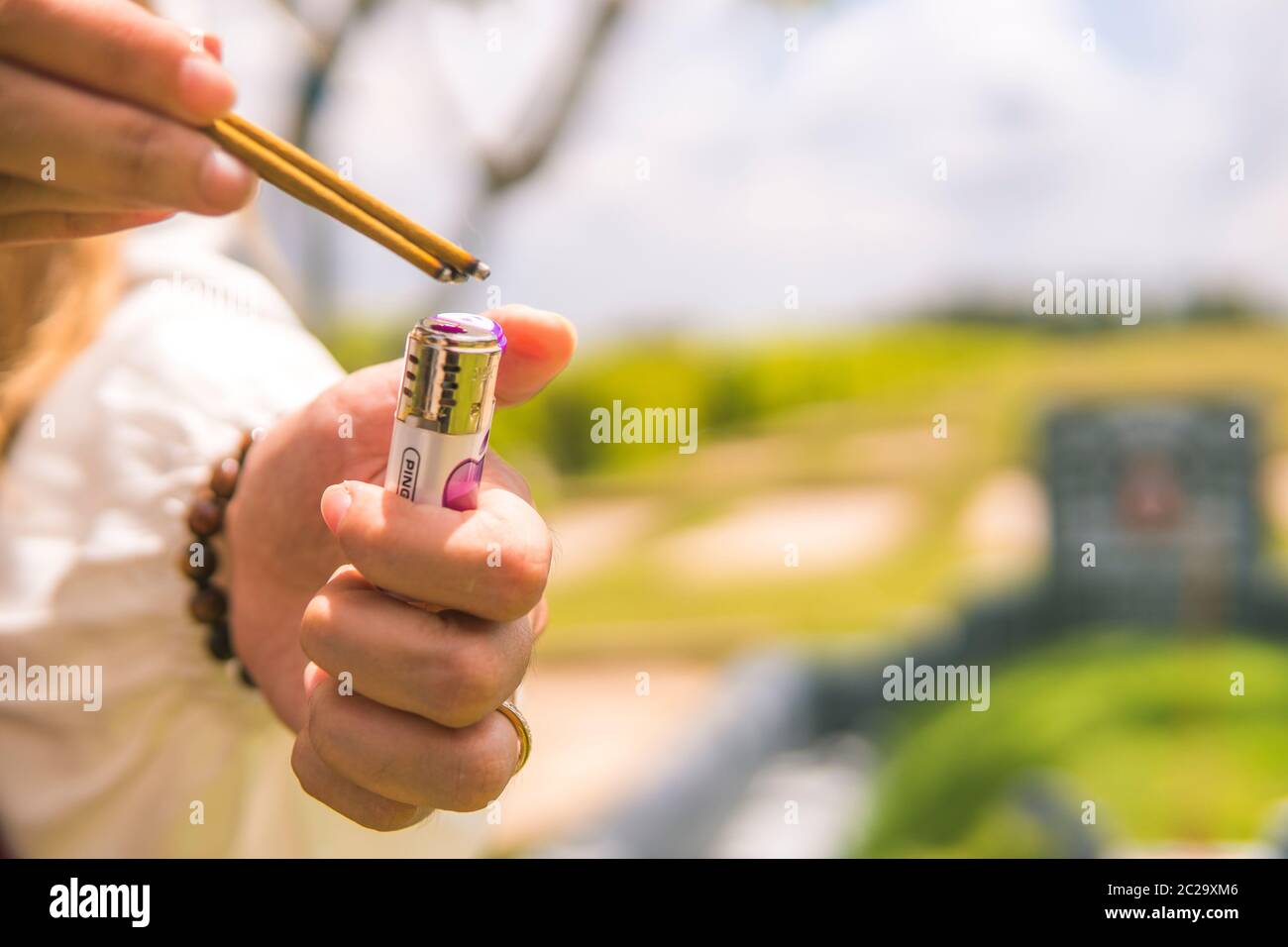 Closeup of a woman's hand burning incense. The background is an