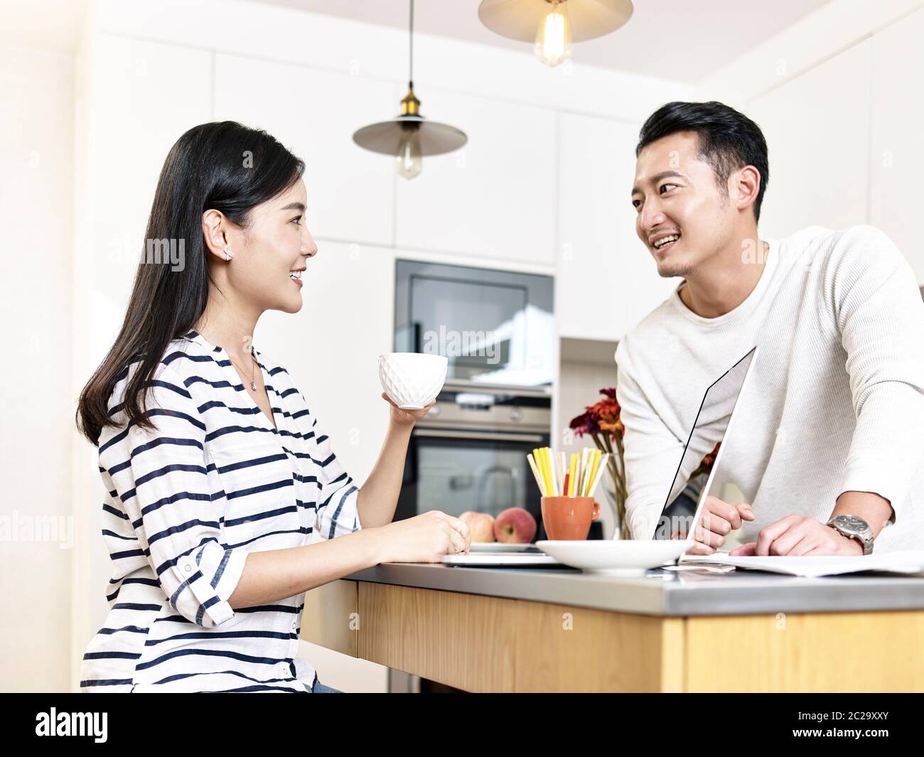 young asian couple working from home sitting kitchen counter having a discussion Stock Photo