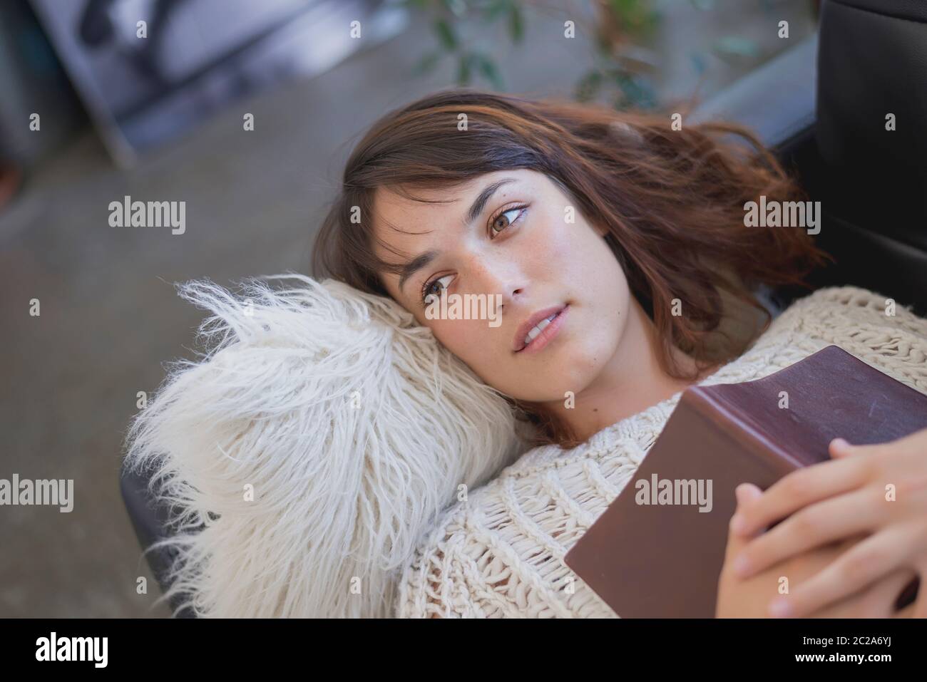 Young tired young woman lying on a sofa with a book Stock Photo - Alamy