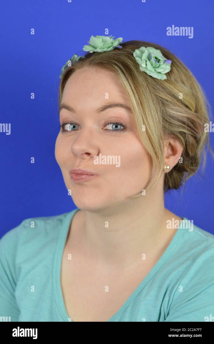 sceptical young blond woman with flowers on a hair circlet Stock Photo