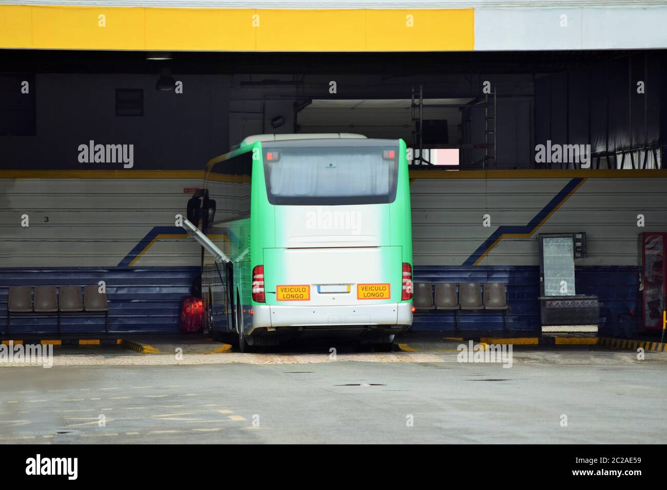 Green and white bus in an open bus station on platform two Stock Photo