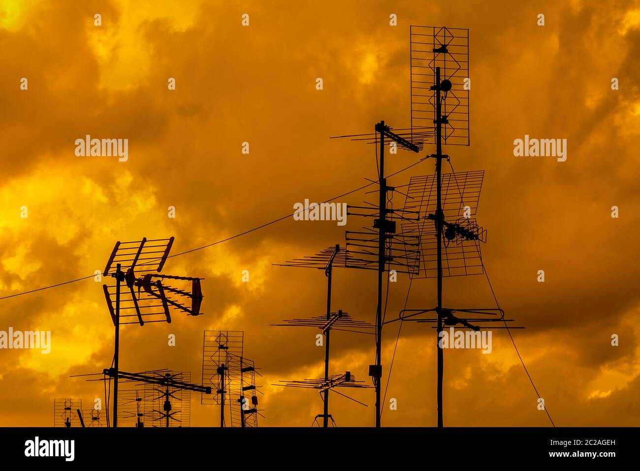 Different kinds of TV antennas and arrays with golden sunset sky and clouds Stock Photo