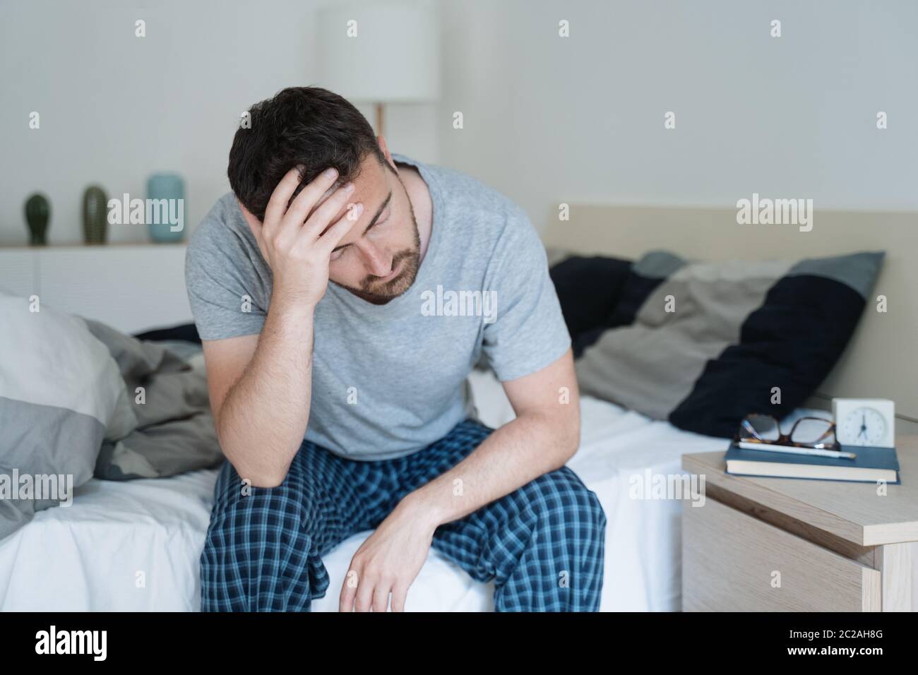 Restless man waking up early with headache after rough night Stock