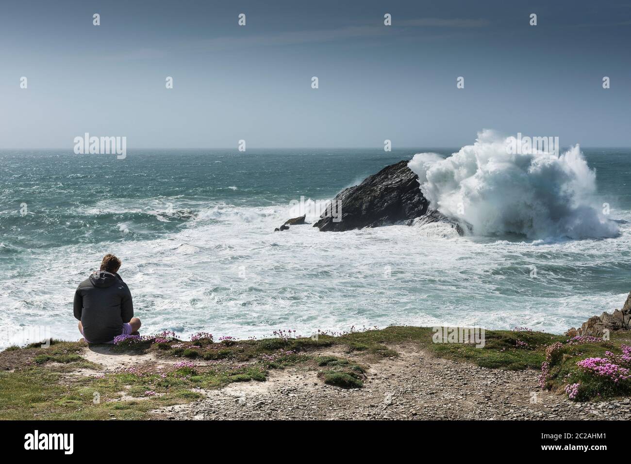 A tourist enjoying the dramatic view from Pentire Point East on the coast of Newquay in Cornwall. Stock Photo