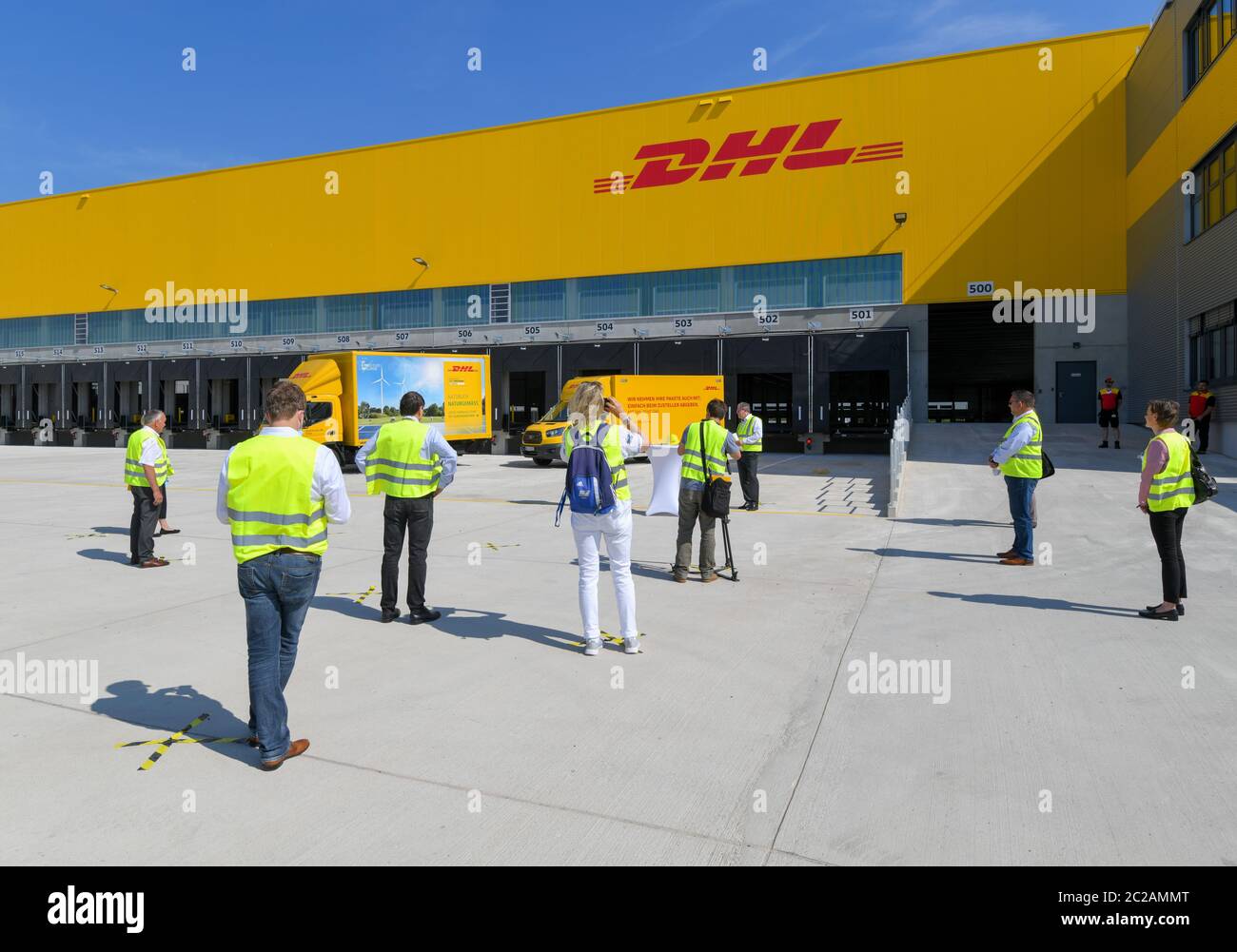 17 June 2020, Brandenburg, Ludwigsfelde: Participants of a press conference are standing in front of the new building of a parcel centre of the Deutsche Post. On the same day, the first construction phase was completed with the completion of the shell for the new parcel centre. In future, up to 50,000 parcels per hour will be sorted in the parcel center. According to the company, the third DHL 'mega parcel centre' in Germany and one of the most modern in Europe is being built on around 165,000 square metres. More than 600 new jobs will be created in the region. Photo: Patrick Pleul/dpa-Zentral Stock Photo