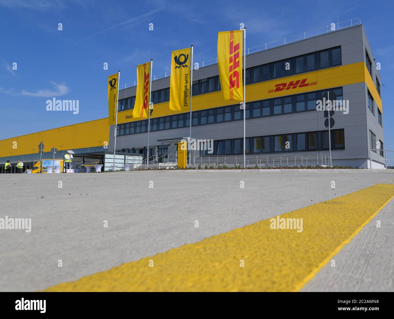 Ludwigsfelde, Germany. 17th June, 2020. Flags are waving in front of the new parcel centre of the Deutsche Post. On the same day, the first construction phase was completed with the completion of the shell for the new parcel centre. In future, up to 50,000 parcels per hour will be sorted in the parcel centre. According to the company, the third DHL 'mega parcel centre' in Germany and one of the most modern in Europe is being built on around 165,000 square metres. More than 600 new jobs will be created in the region. Credit: Patrick Pleul/dpa-Zentralbild/dpa/Alamy Live News Stock Photo