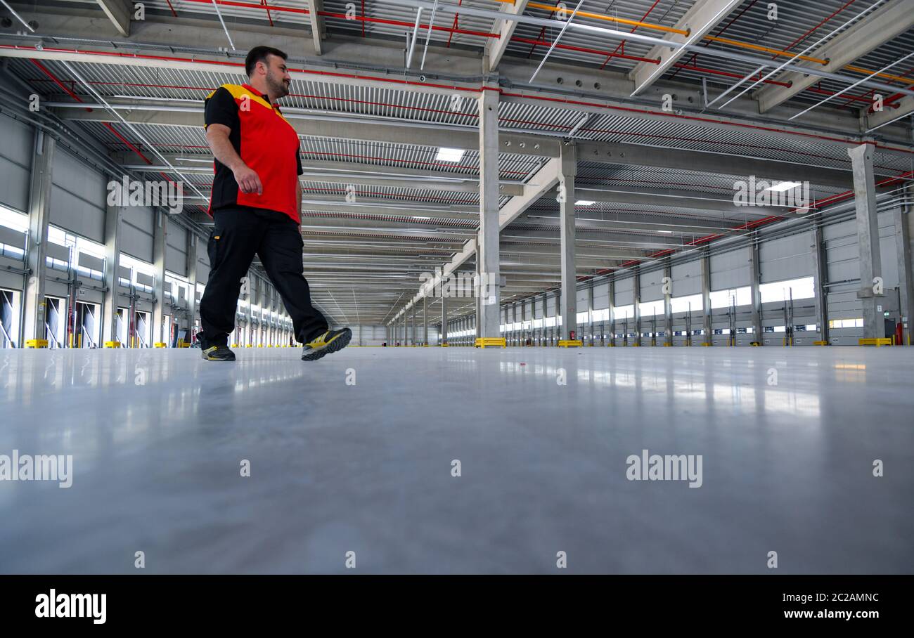Ludwigsfelde, Germany. 17th June, 2020. A delivery person walks through the empty shell of a Deutsche Post parcel centre. On the same day, the first construction phase was completed with the completion of the shell for the new parcel centre. In future, up to 50,000 parcels per hour will be sorted in the parcel centre. According to the company, the third DHL 'mega parcel centre' in Germany and one of the most modern in Europe is being built on around 165,000 square metres. More than 600 new jobs will be created in the region. Credit: Patrick Pleul/dpa-Zentralbild/dpa/Alamy Live News Stock Photo