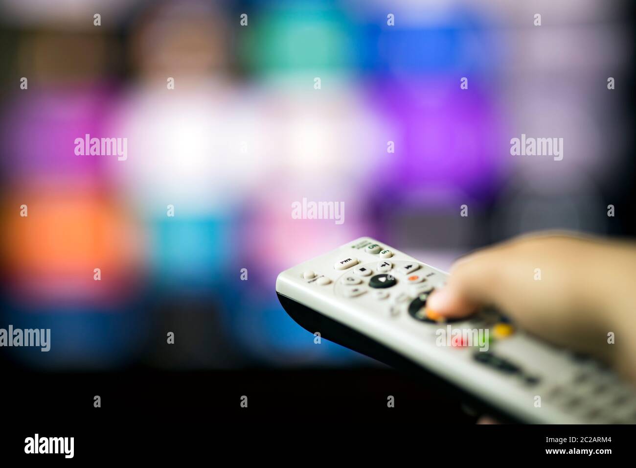 Remote control in hand in from of smart tv Stock Photo