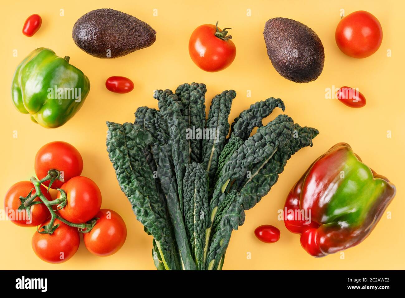Black curly italian kale, tomatoes, avocado, pepper on orange background. Stock Photo