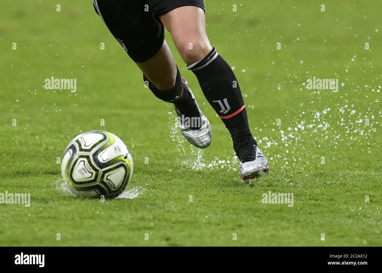 Close up legs of female soccer players action, on a wet green soccer field. Stock Photo