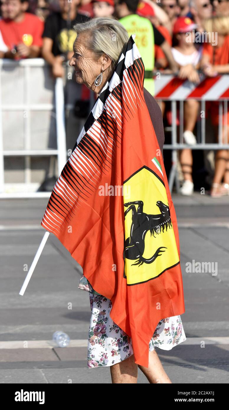 Ferrari elderly woman fan with a Ferrari flag in Duomo square to celebrate the 90th anniversary of the Ferrari , in Milan. Stock Photo